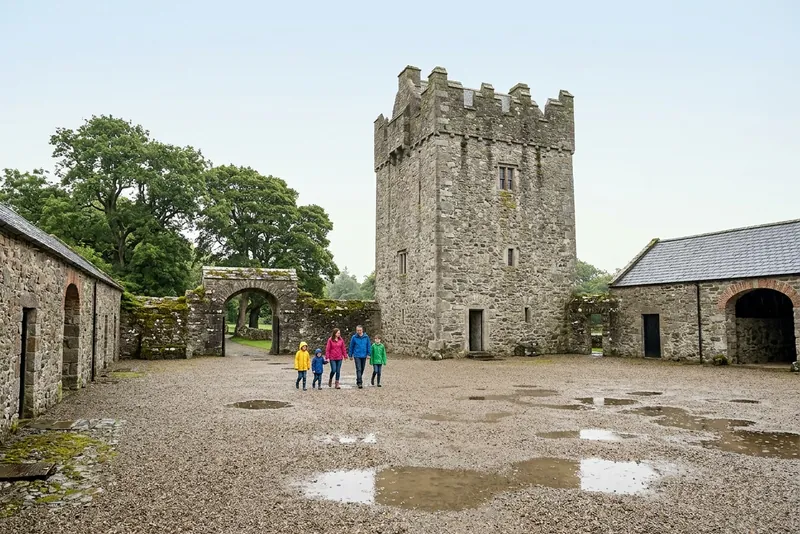 A family crossing the gravel farmyard below the tower house at Castle Ward, Winterfell on screen