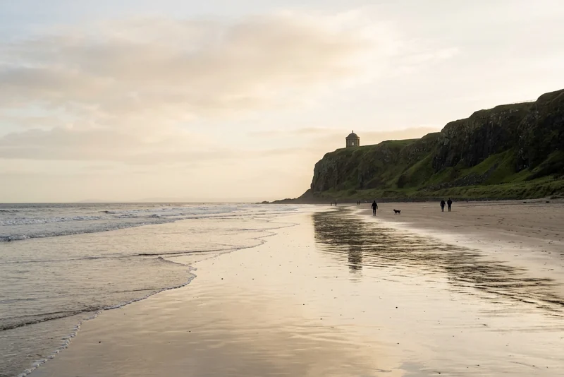 Walkers on Downhill Strand at dusk below Mussenden Temple, the Dragonstone beach on screen