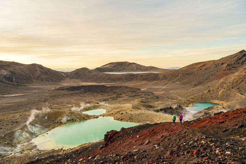 Two hikers above the steaming Emerald Lakes on the Tongariro Alpine Crossing