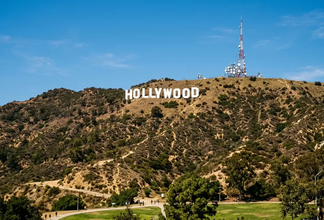 The Hollywood Sign on the brushy slope of Mount Lee, with a park path below