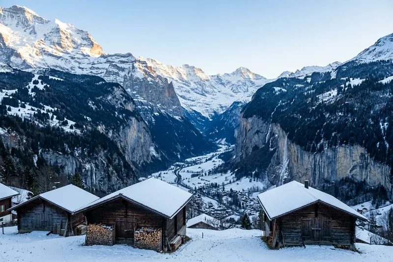 Snowy wooden huts above the Lauterbrunnen valley in winter, with the Bernese Alps beyond