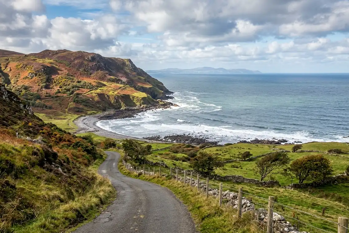 A narrow lane winding down between stone walls toward Murlough Bay on the Antrim coast