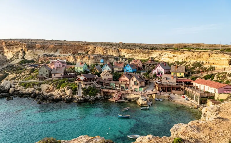 The colorful wooden Popeye Village film set across the turquoise water of Anchor Bay, Malta