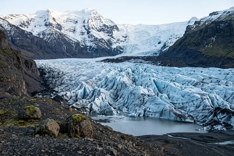 The crevassed ice of the Svínafellsjökull glacier flowing down between dark mountains near Skaftafell