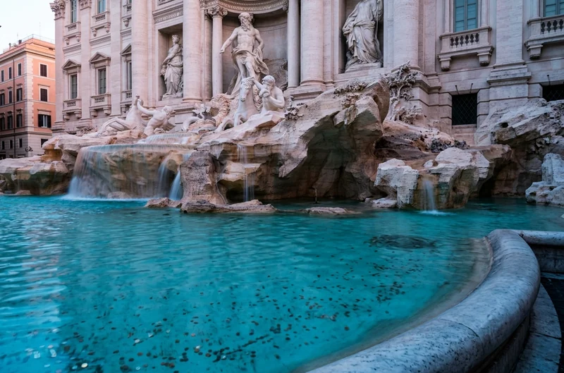 The Trevi Fountain at dawn, its turquoise pool full of coins below the statue of Oceanus